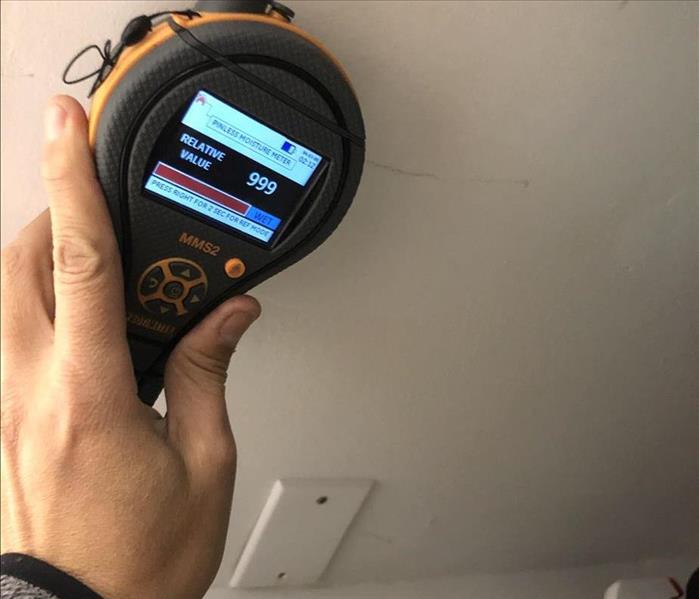 Moisture meter reading 999 determining the wall is wet.